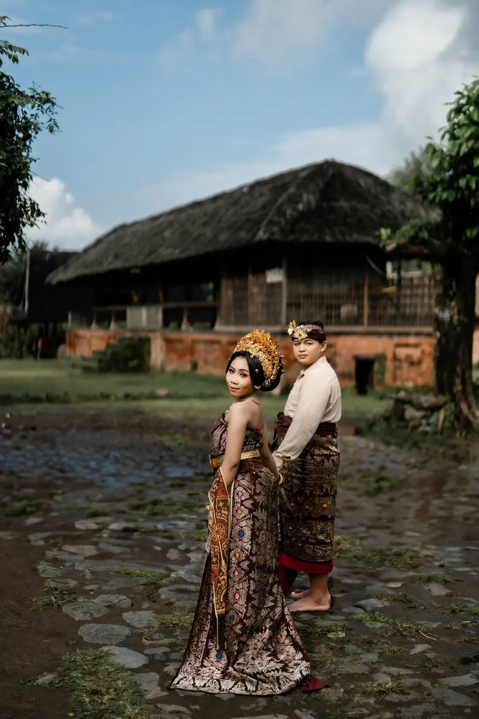 Kedua mempelai berbusana adat Bali di halaman desa