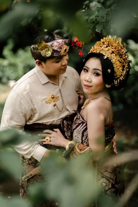 Kedua mempelai berpelukan di antara dedaunan