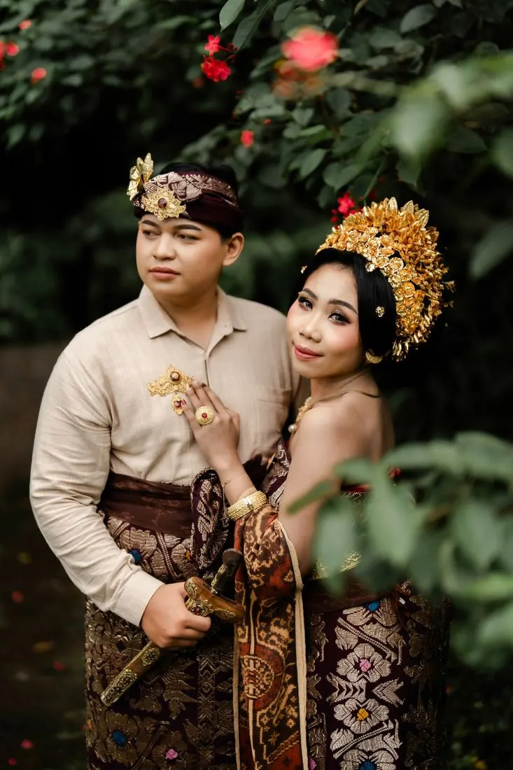 Kedua mempelai berdampingan di antara dedaunan
