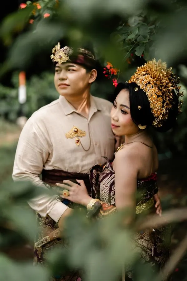 Kedua mempelai berpelukan di antara dedaunan